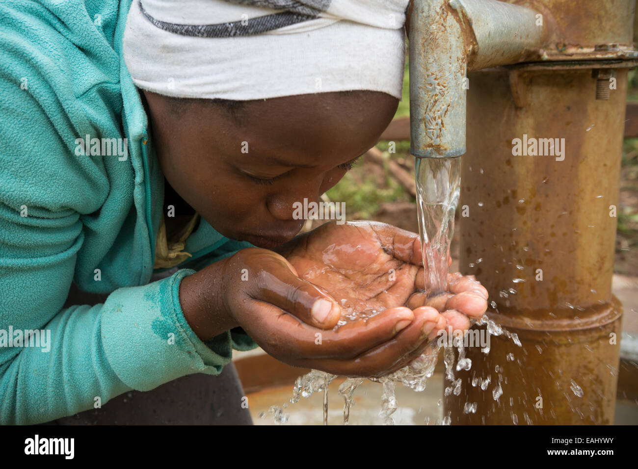 Une adolescente la fraîcheur des boissons, de l'eau propre du bien nouvellement installé dans son village dans le district de Bukwo, est de l'Ouganda, Eas Banque D'Images