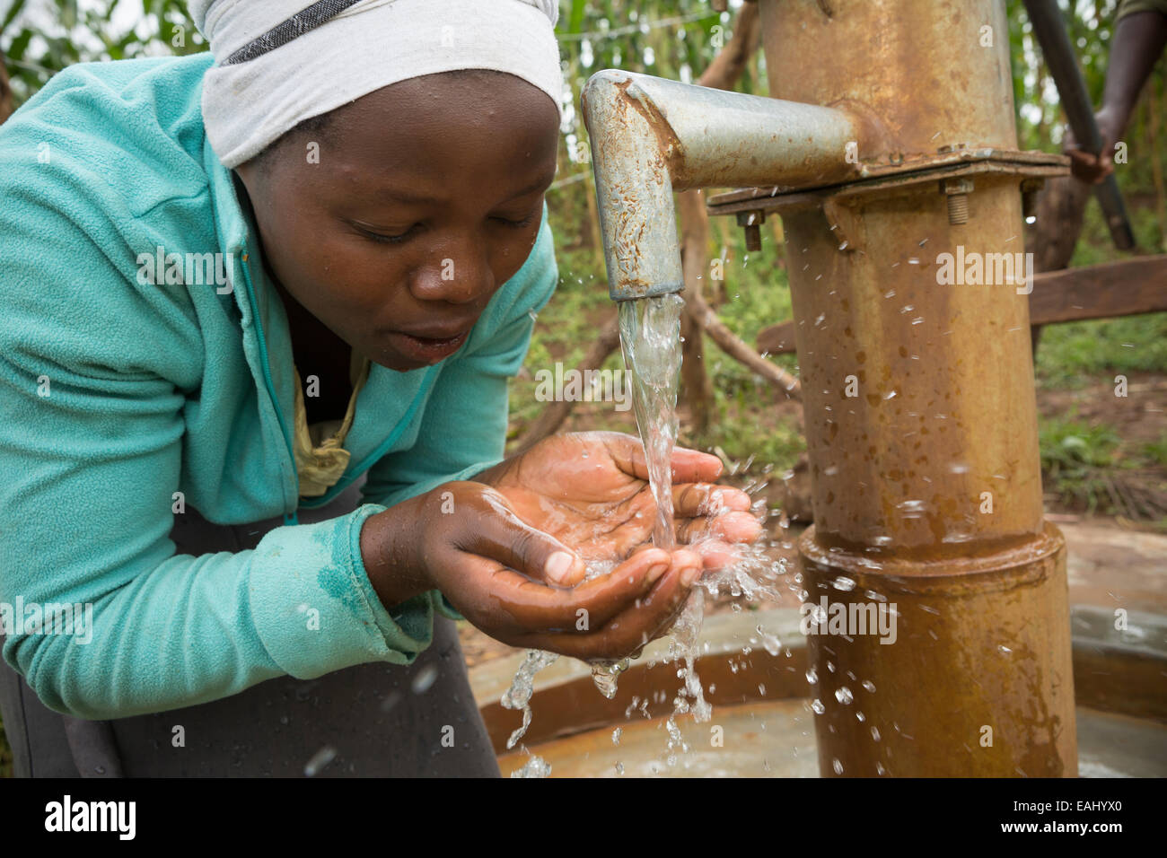 Une adolescente la fraîcheur des boissons, de l'eau propre du bien nouvellement installé dans son village dans le district de Bukwo, est de l'Ouganda, Eas Banque D'Images