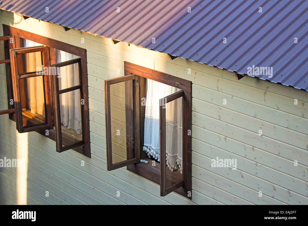 Détail de la façade de la maison, éclairée par le soleil du soir, avec les fenêtres ouvertes. Banque D'Images