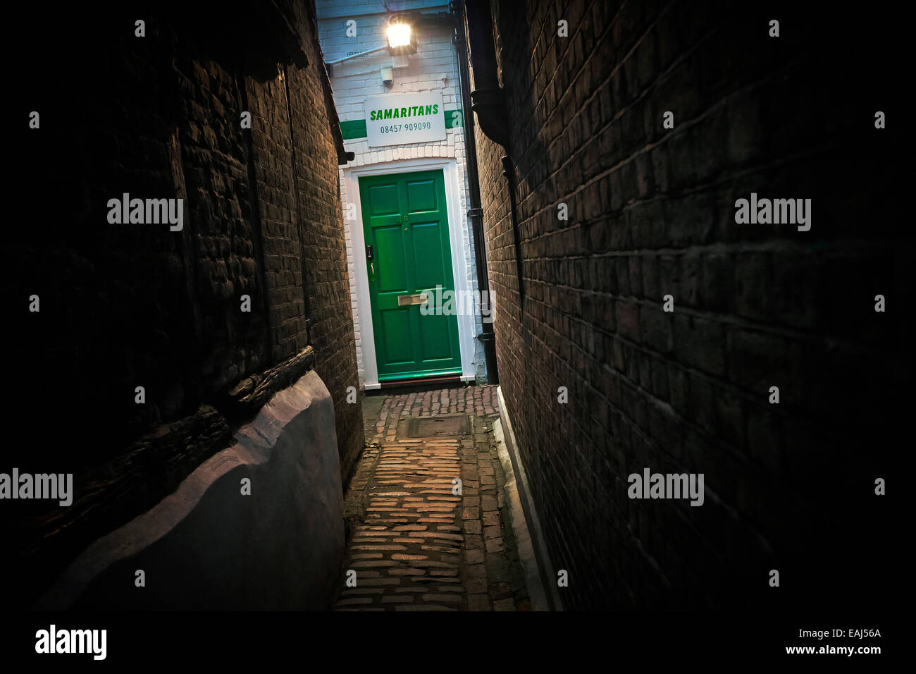 ' La lumière au bout du tunnel ' - Samaritains offices en signe et porte verte au-delà de ruelle. Banque D'Images