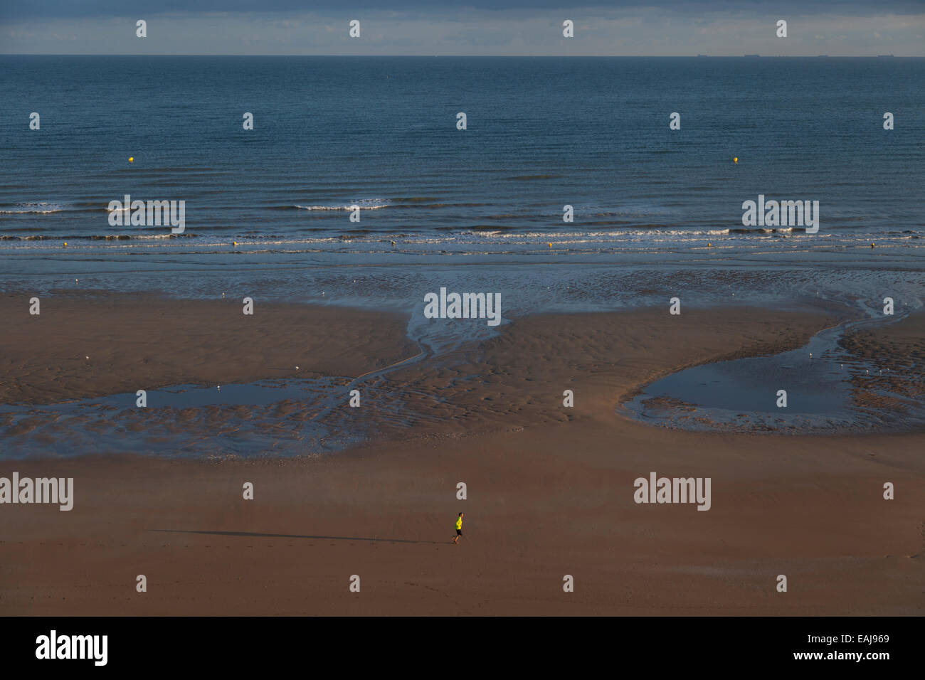 Tôt le matin sur la plage de Cabourg, en Normandie, avec un seul jogger en premier plan Banque D'Images