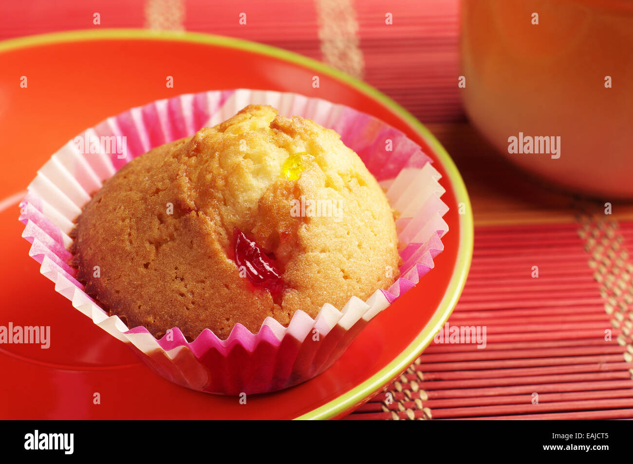 Muffins savoureux en plaque rouge sur serviette en bambou coloré Banque D'Images