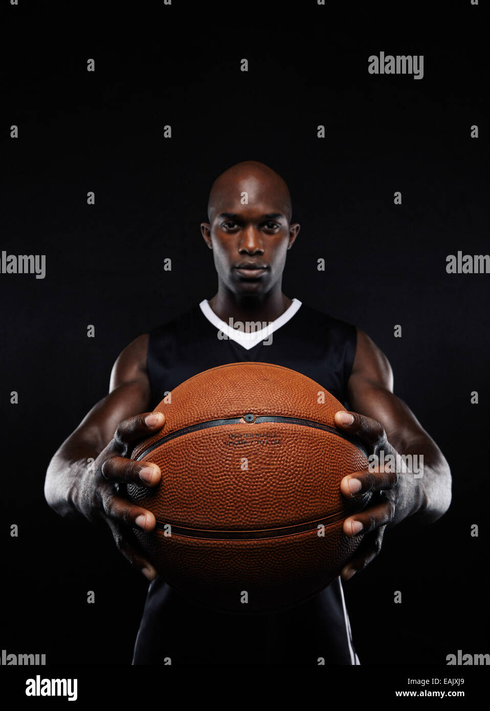 Portrait de joueur de basket-ball africain professionnel avec une balle à l'arrière-plan noir. Fit young man holding basket-ball. Banque D'Images