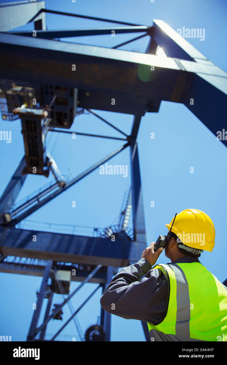Low angle view of worker using walkie-talkie près de crane Banque D'Images