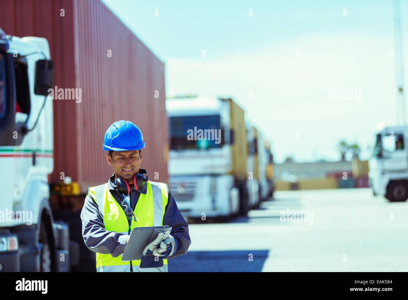 Worker using digital tablet près de camions avec les conteneurs de fret Banque D'Images
