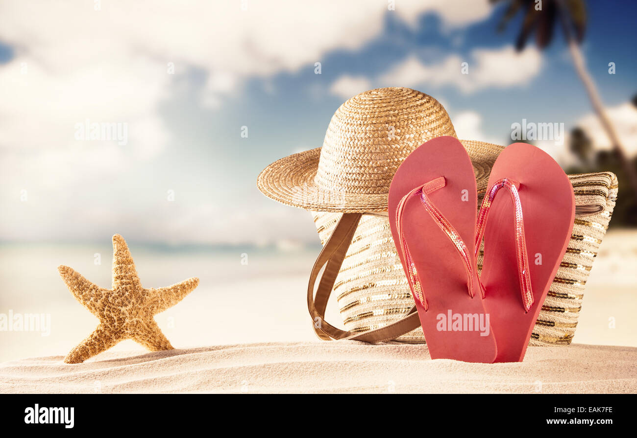 Concept d'été avec plage de sable, de coquillages et de sandales rouge Banque D'Images