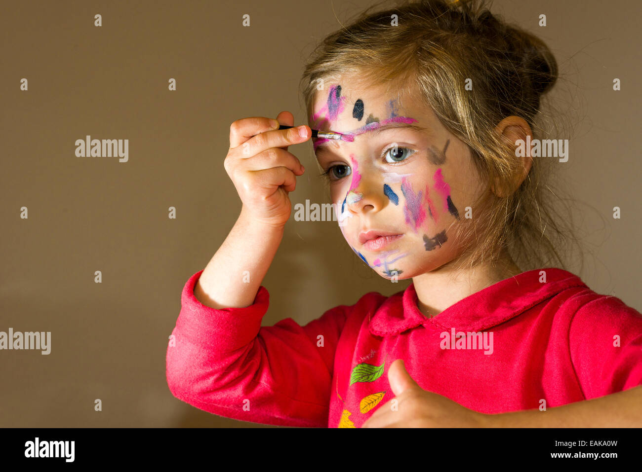 Girl painting son visage aux couleurs aquarelle, Allemagne Banque D'Images