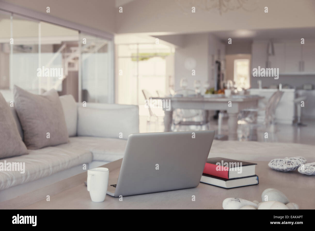 Salon moderne intérieur avec ordinateur portable, livres et mug sur la table Banque D'Images
