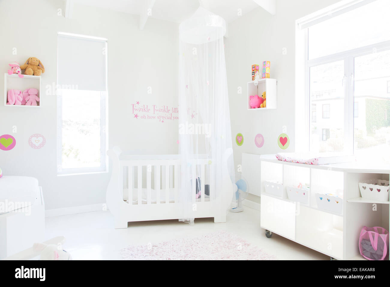 Lit bébé blanc avec tulle auvent dans la chambre de bébé de couleur pastel Banque D'Images