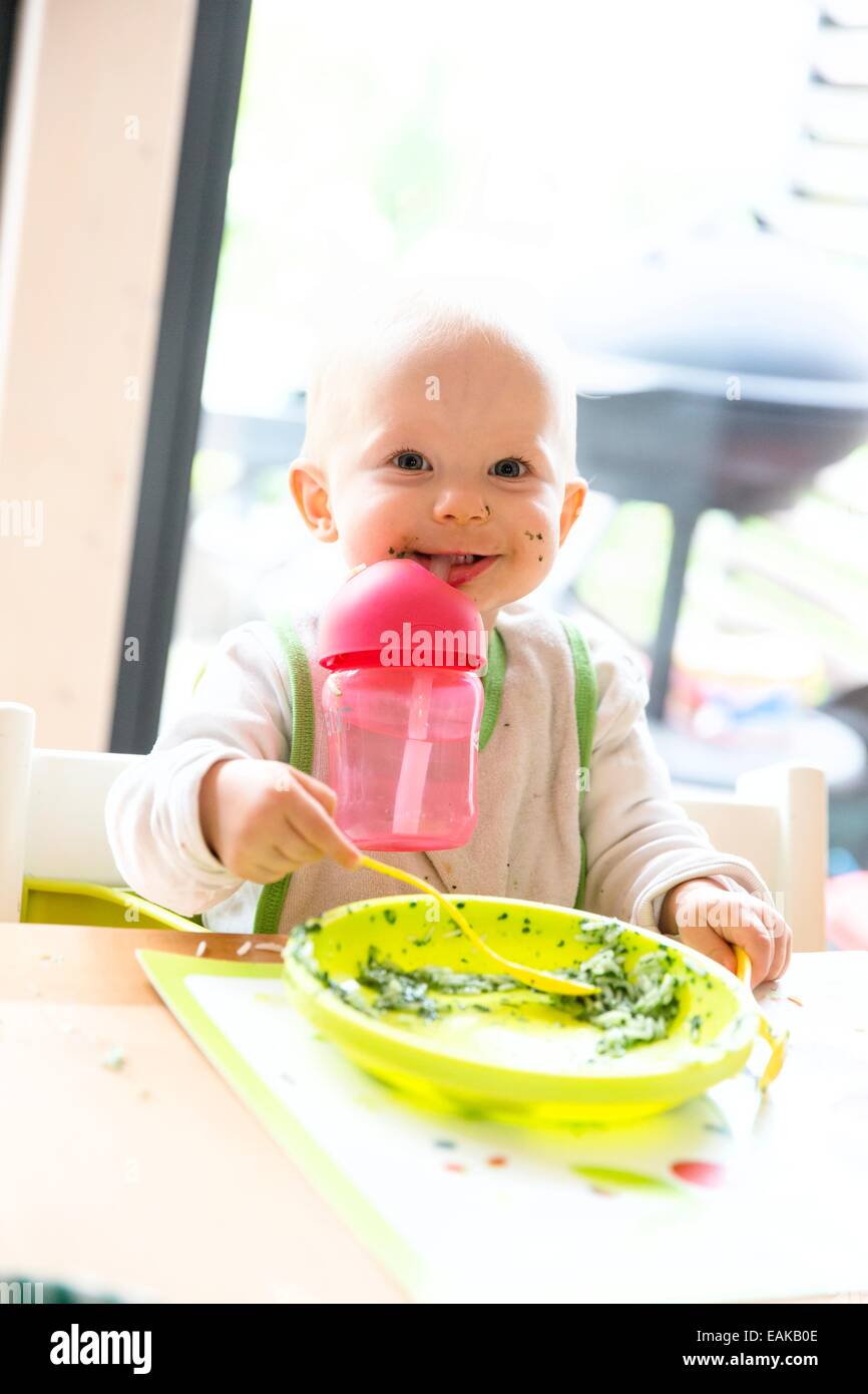 Bébé, de 12 à 14 mois, avec la plaque et tasse Banque D'Images