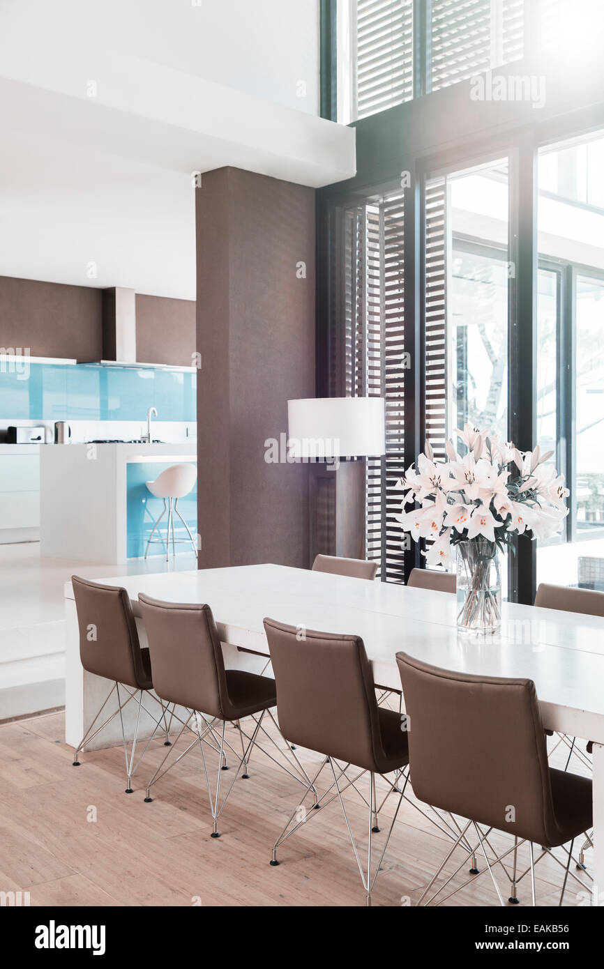 Vue de salle à manger moderne avec des lys blancs dans un vase sur la table Banque D'Images