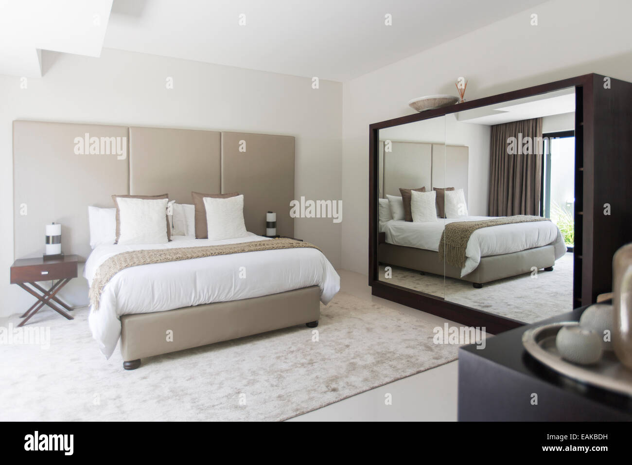 Beige et blanc chambre moderne avec lit double mirror Banque D'Images