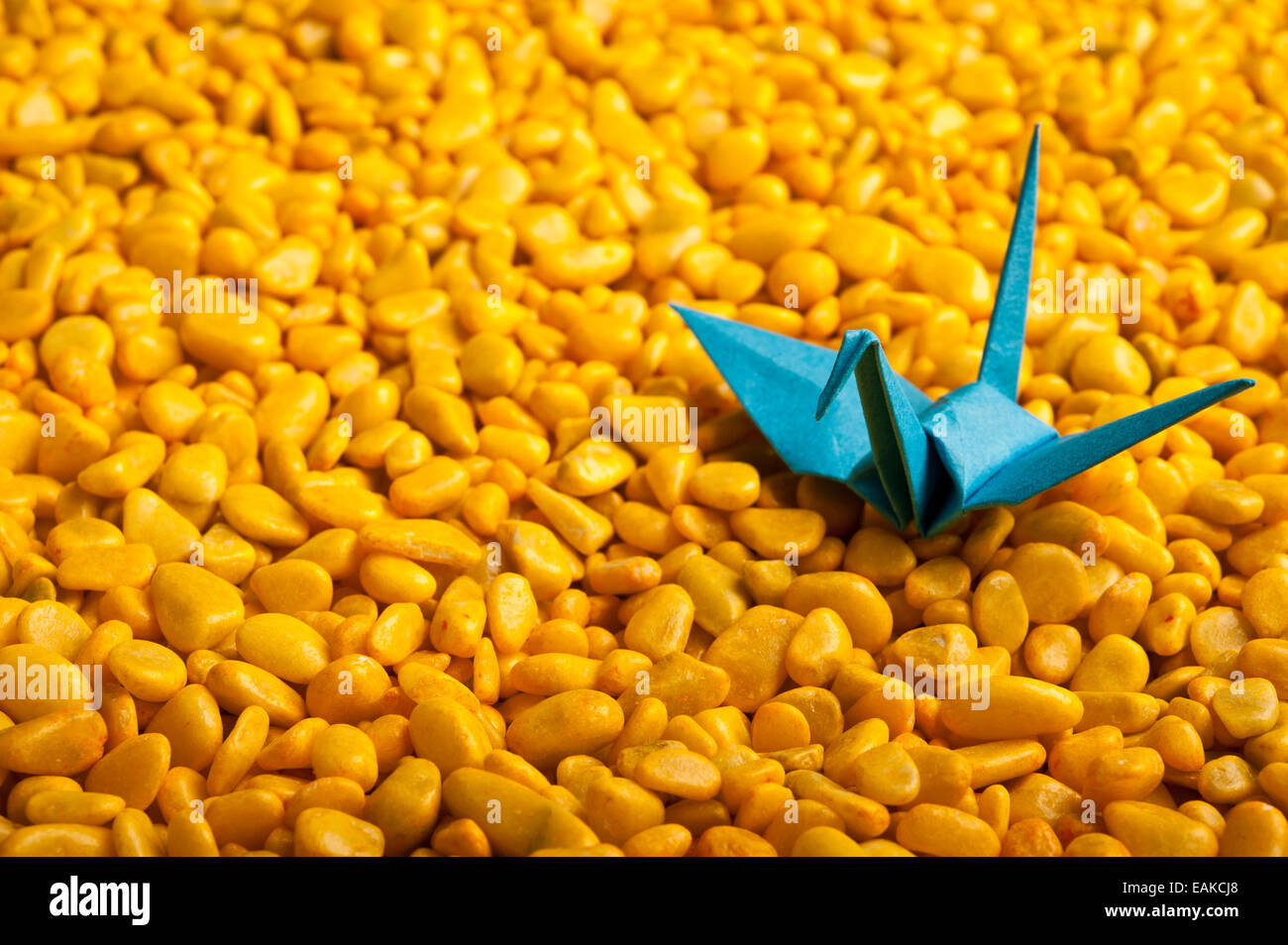 Oiseau origami bleu sur fond jaune de cailloux Banque D'Images