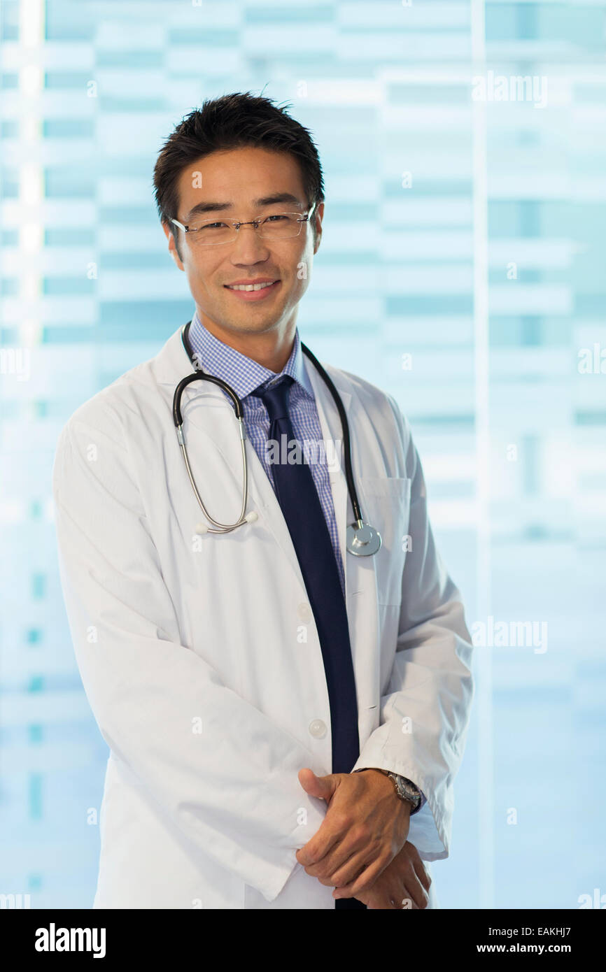 Portrait of smiling doctor portant des lunettes et manteau de laboratoire standing in hospital Banque D'Images