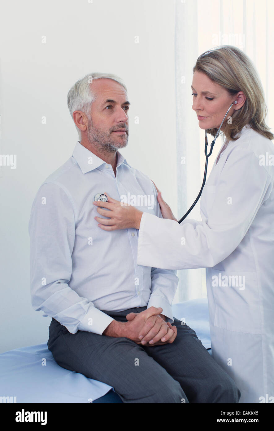 Femme médecin examinant son patient with stethoscope in office Banque D'Images