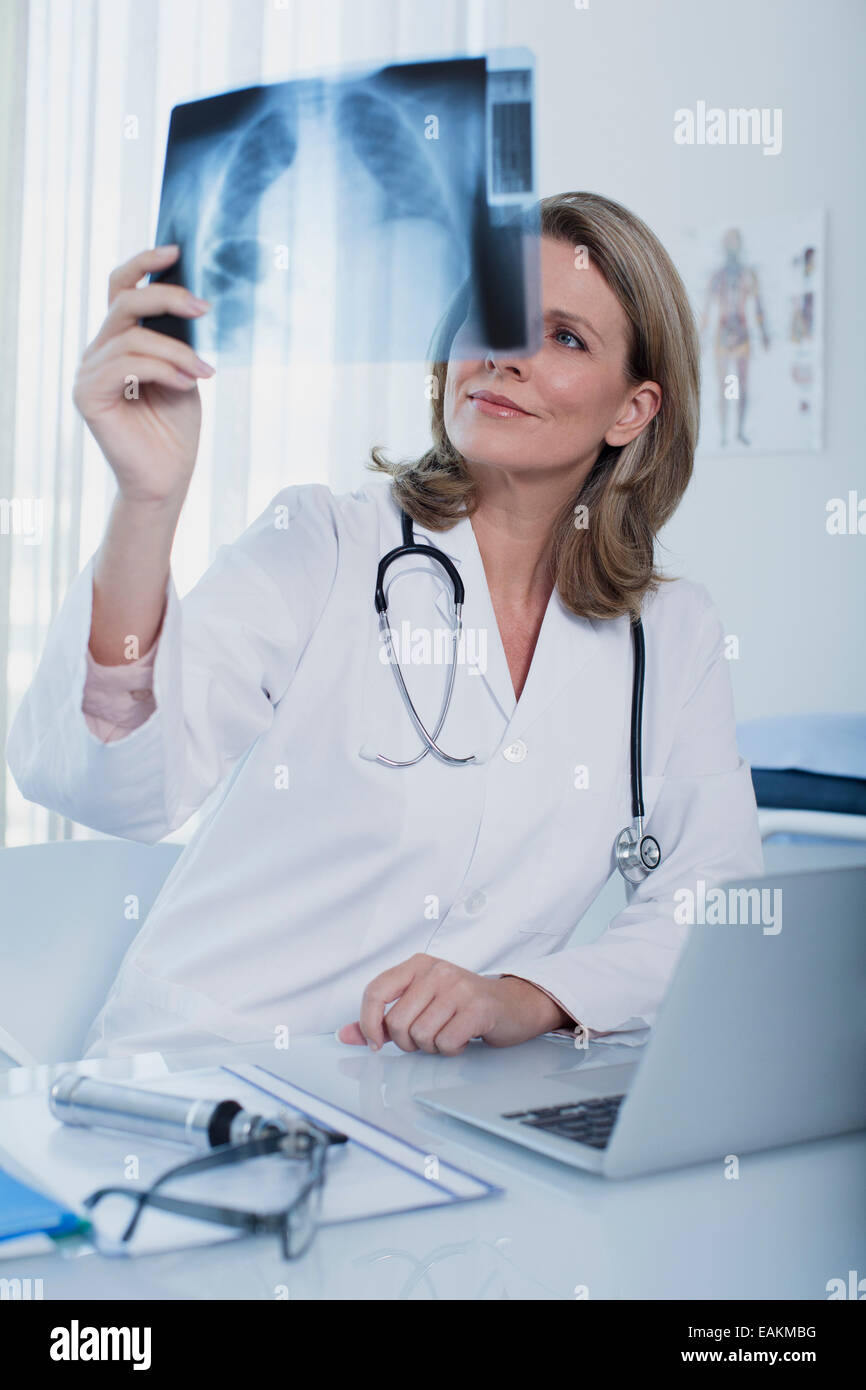 Femme médecin à la recherche de x-ray à 24 avec laptop in office Banque D'Images