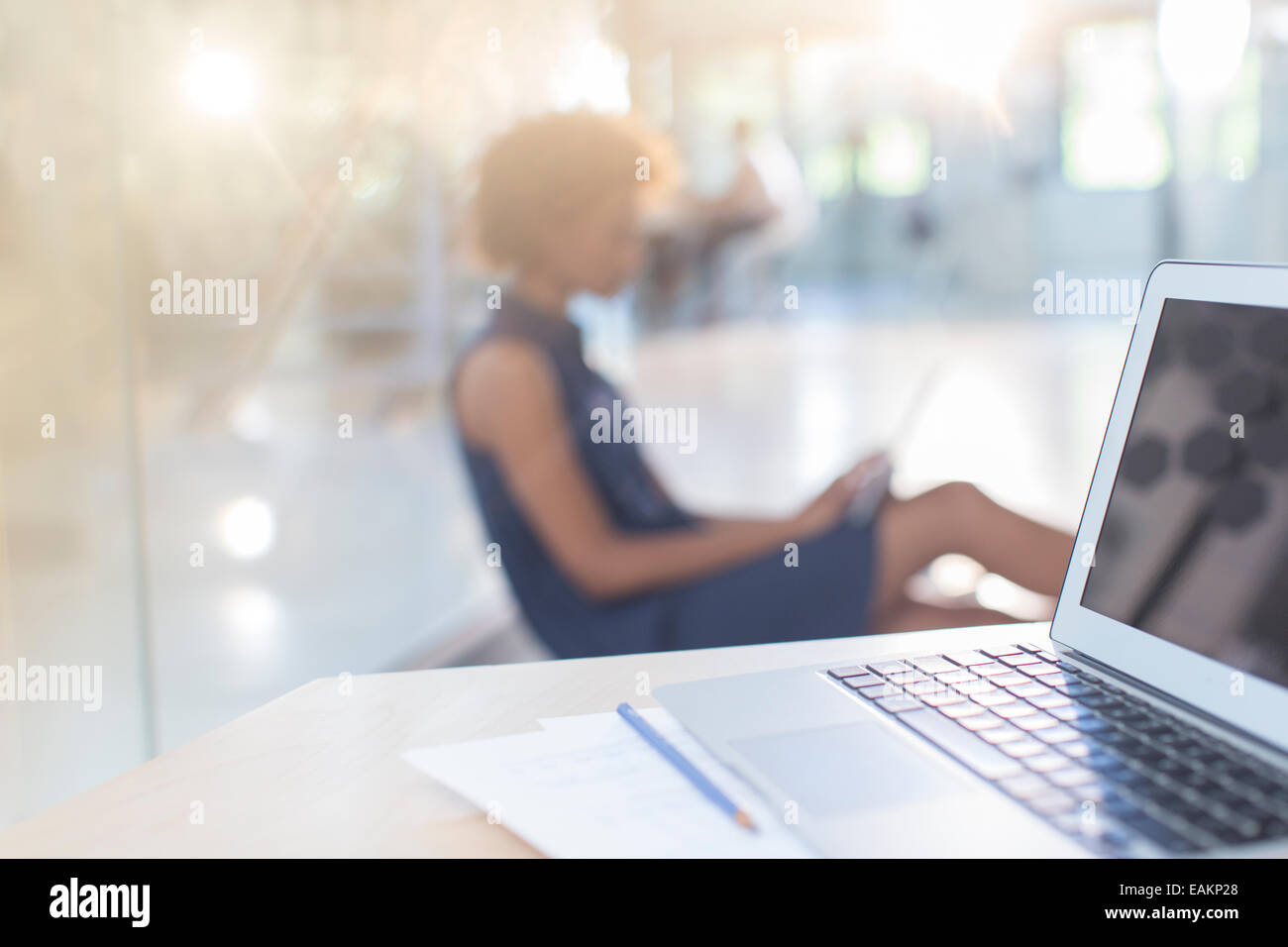 Ouvrez l'ordinateur portable sur 24, woman in background Banque D'Images