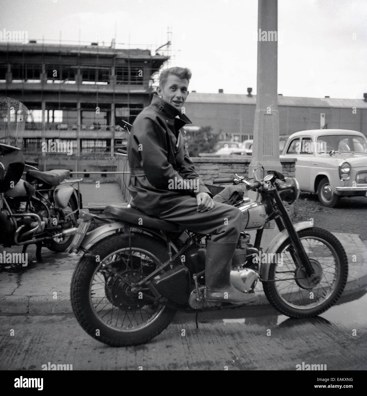 Années 1950, historique, un homme portant une veste de motard et des bottes wellington assis à l'extérieur sur sa moto Triumph, qui a un emblème de jack d'Union rayé sur le réservoir d'essence, Angleterre, Royaume-Uni. Banque D'Images