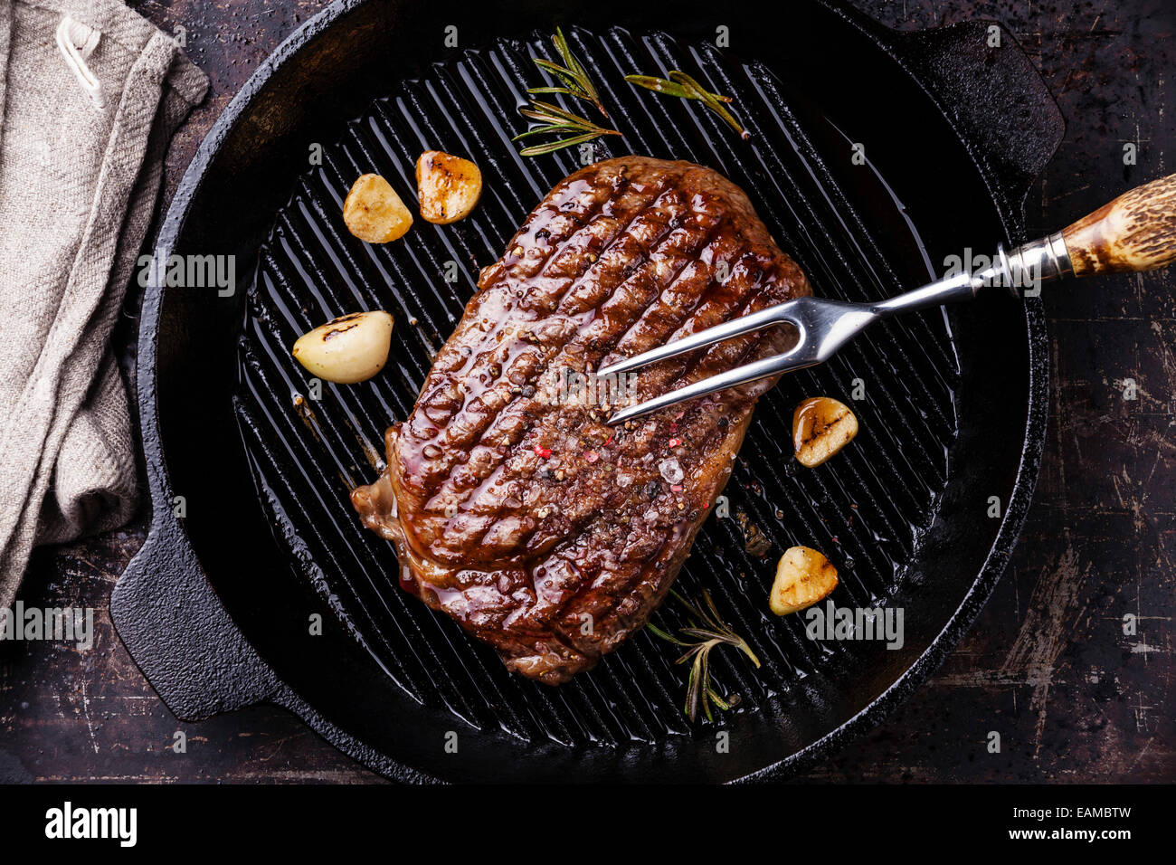 Ribeye Steak grillé et fourchette à viande sur gril sur fond sombre Banque D'Images