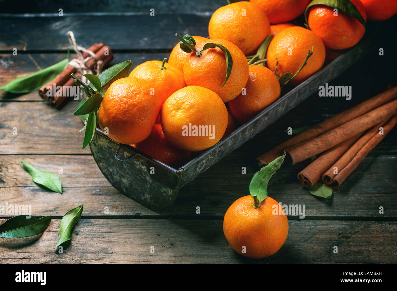 Mandarines avec les feuilles et le bâton de cannelle sur la vieille table en bois. Banque D'Images