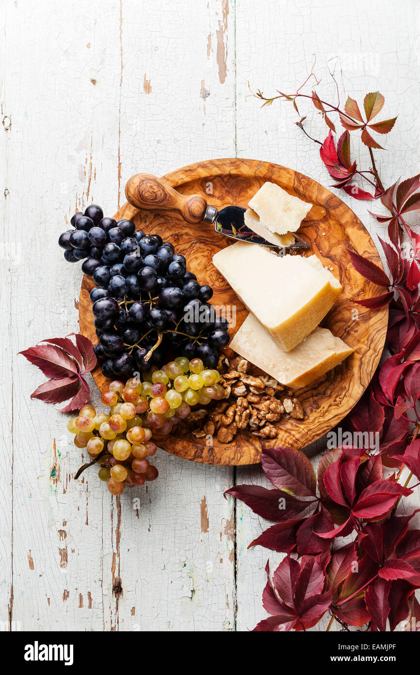 Le Parmesan, les raisins et les noix sur la plaque en bois d'olivier Banque D'Images