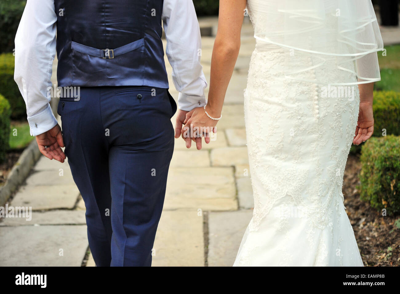 Couple de jeunes mariés à pied se tenant la main. Banque D'Images