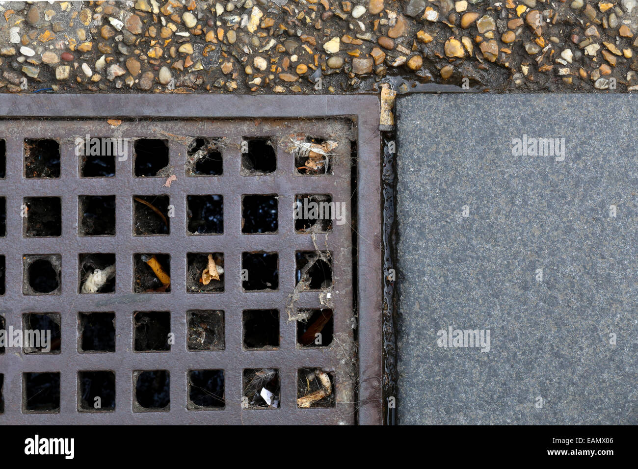 Grille métallique d'égoût dans une allée d'asphalte et dalles en pierre grise de la chaussée, rue grunge background Banque D'Images