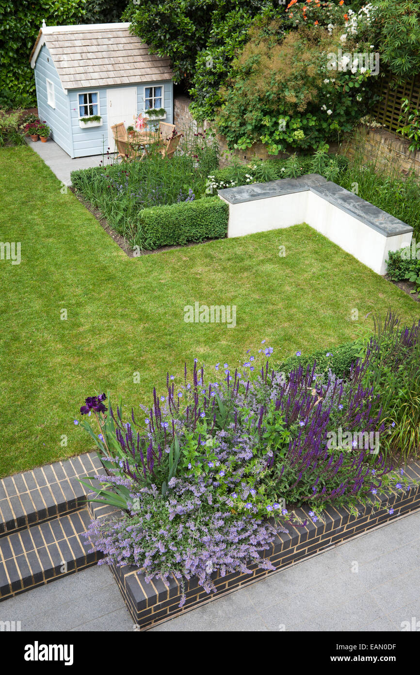 Soulevées bed construit en brique gris violet et rouge foncé avec la plantation avec playhouse de coin dans le jardin moderne, Londres Banque D'Images