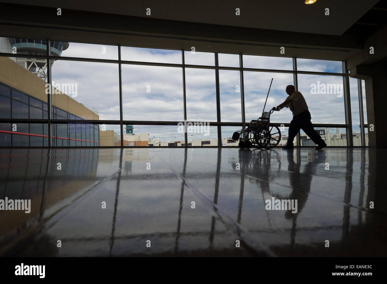 En poussant l'homme en fauteuil roulant vide passé Fenêtre Airport Banque D'Images