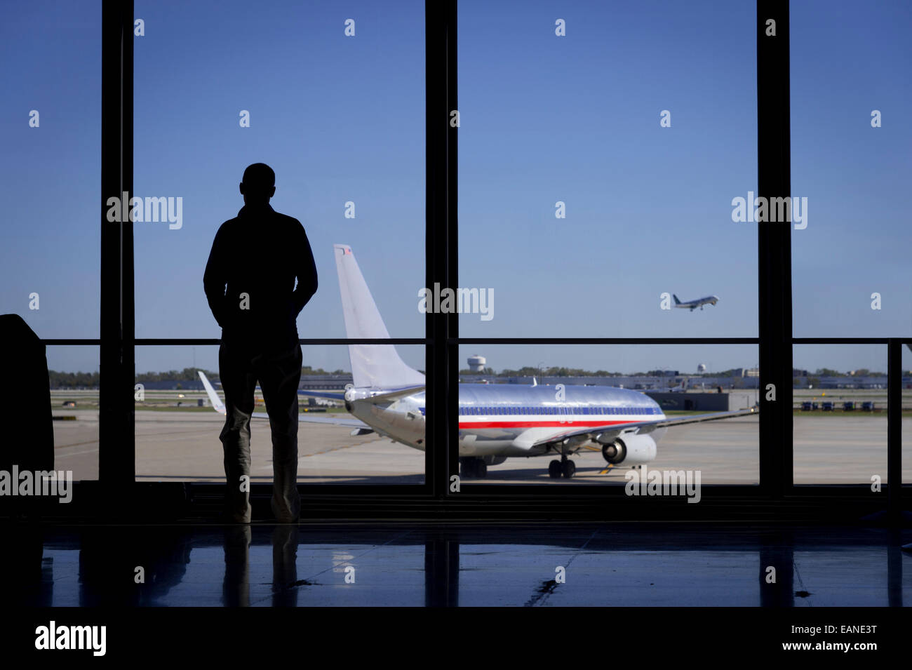 Homme debout regardant à la fenêtre à regarder les avions de l'aéroport Banque D'Images