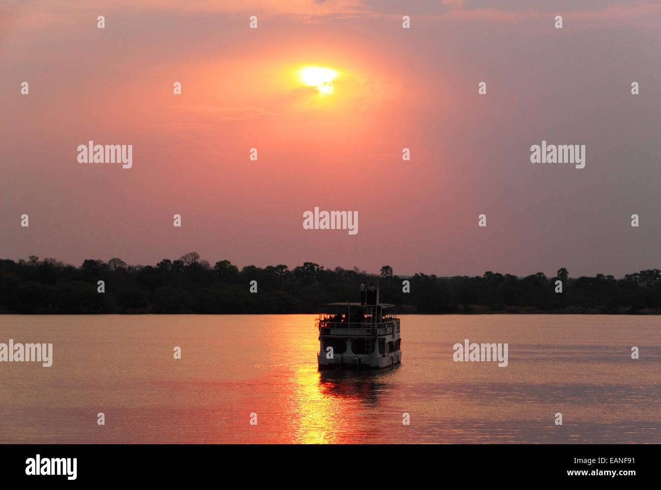 Un bateau de croisière de la rivière africaine silhouette sur le soleil couchant. Banque D'Images