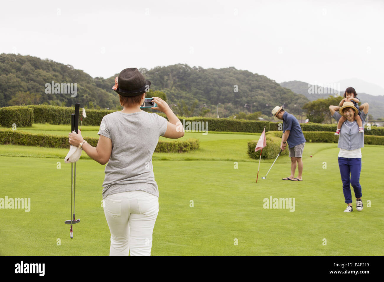 Sur un terrain de golf de la famille.Un enfant et trois adultes. Une femme avec un appareil photo. Banque D'Images