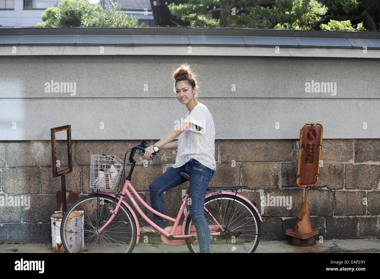 Une femme assise sur un vélo rose. Banque D'Images