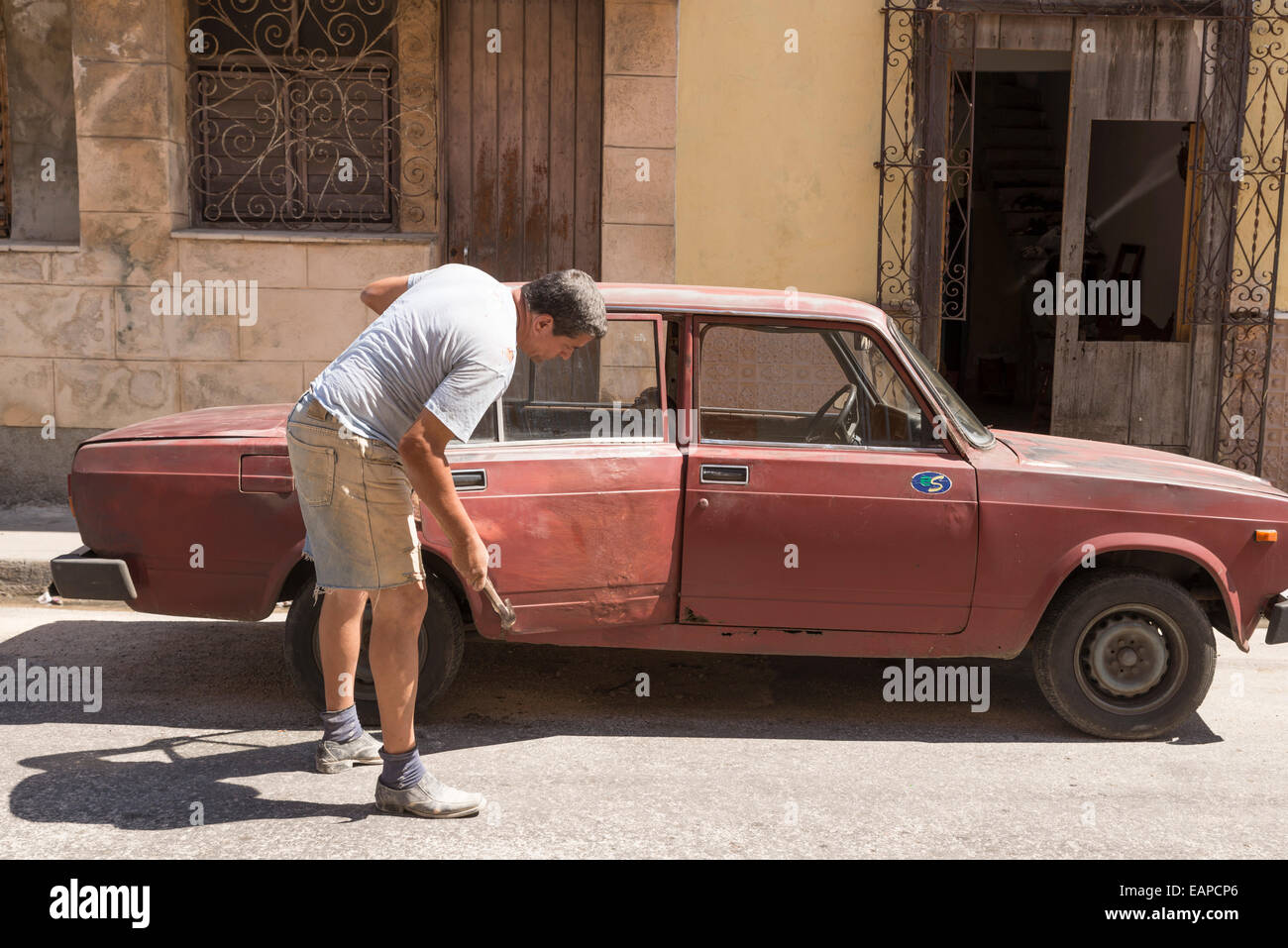 MATANZAS, CUBA - 10 MAI 2014 : dans la rue un homme réparer une porte battues marteler votre vieille voiture Banque D'Images
