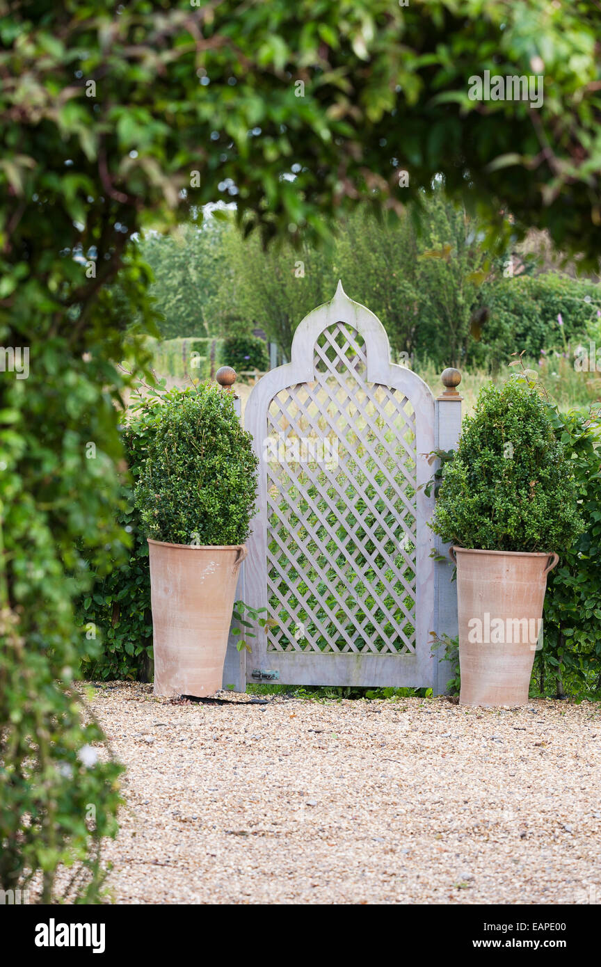 Paire de pots en terre cuite avec couverture de chaque côté de porte de jardin Banque D'Images