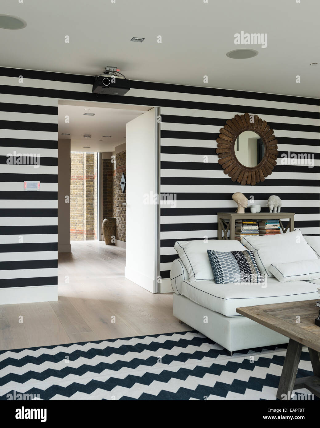 Les murs à rayures noir et blanc dans la salle de séjour avec chevron tapis à motifs. Le canapé est un 5-pièces de Brooklyn à Oka. Banque D'Images