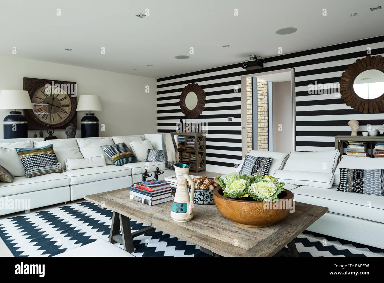 Mur rayé noir et blanc dans la salle de séjour avec chevron tapis à motifs. Le Brooklyn 5-pièces et la table basse en bois les deux c Banque D'Images