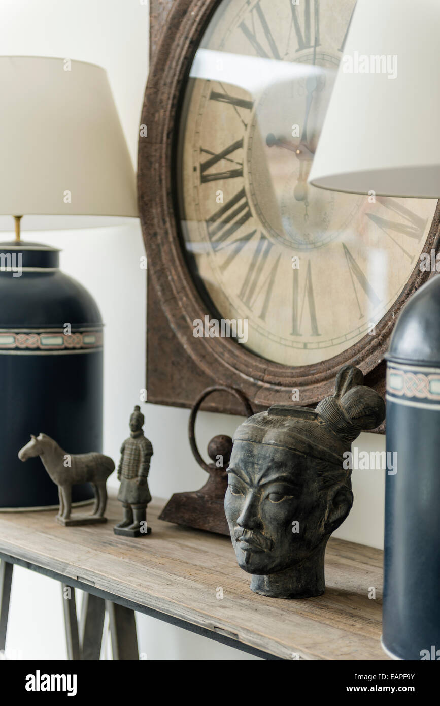 Détail d'antiquités chinoises et d'un plateau/lampes canister sur corniche en bois avec de vieux réveil sur le mur derrière Banque D'Images