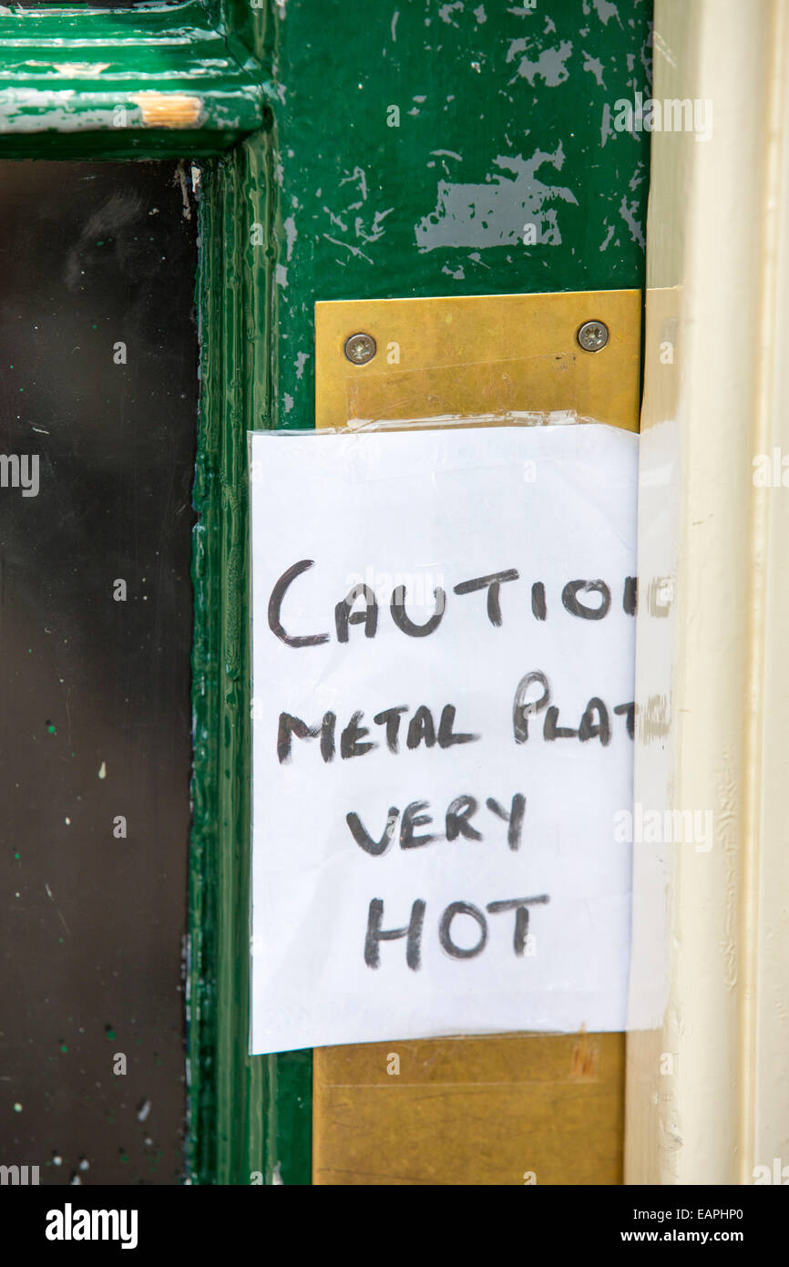 Un signe sur un magasin porte pendant une vague de chaleur, d'avertissement du hot metal plaque de porte, Hexham, Northumberland, Angleterre. Banque D'Images