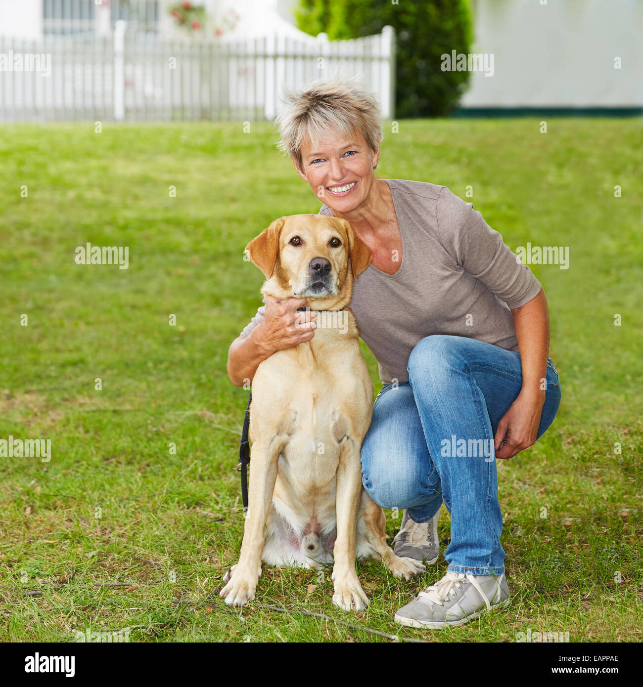 Smiling senior femme assise avec son chien dans le jardin Banque D'Images
