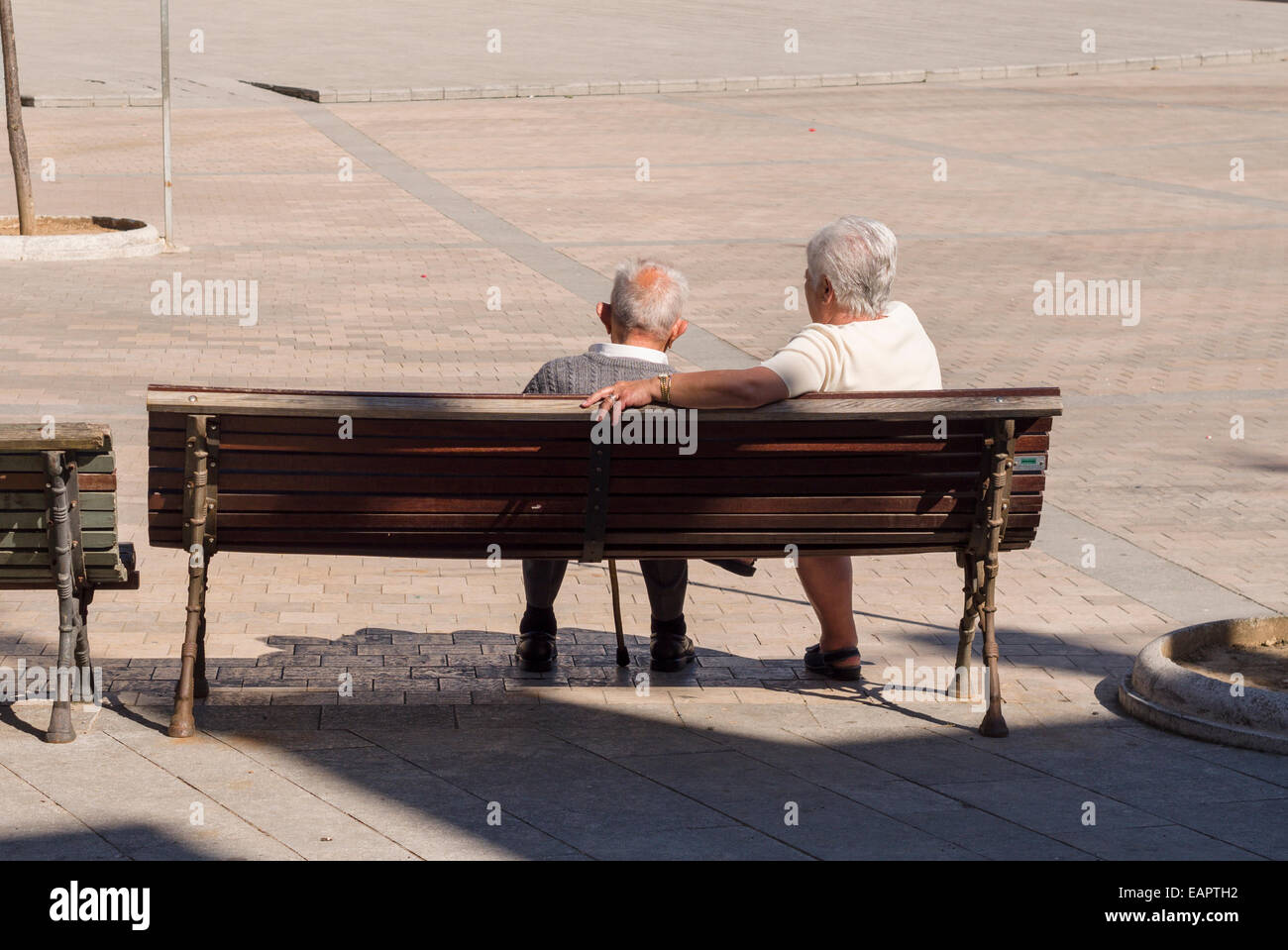 Prendre une pause sur un banc. Un couple plus âgé avec des cheveux blancs prennent une pause sur un banc de la place centrale de Besalu. Banque D'Images