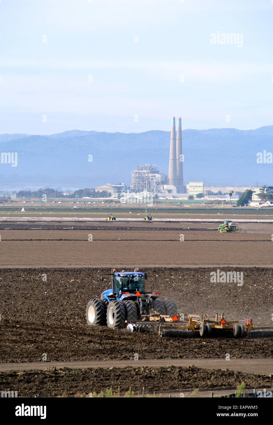Plugh tracteurs champs dans le comté de Monterey près de Castroville et la Moss Landing power plant Banque D'Images