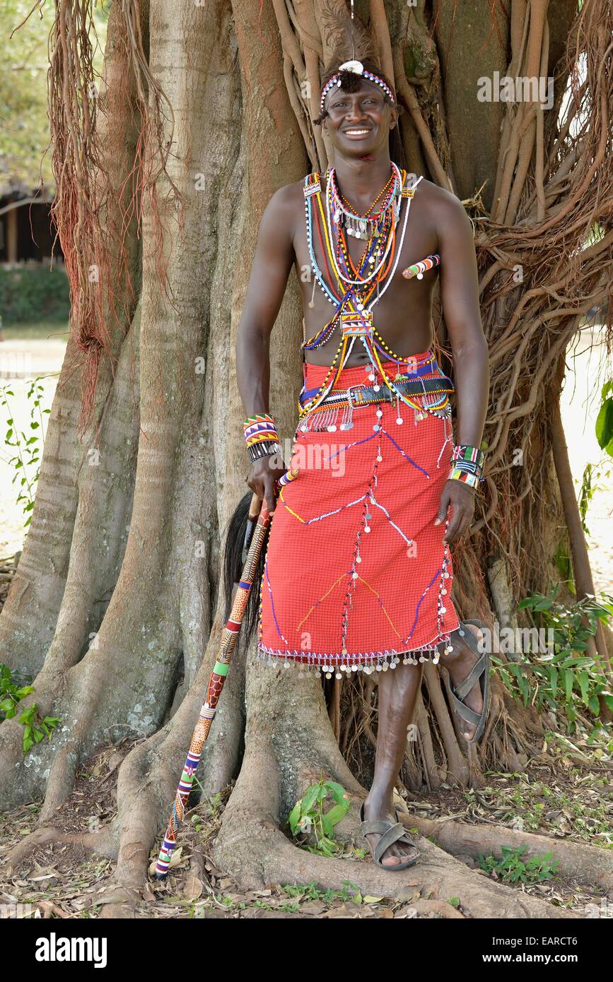Guerrier massaï portant des vêtements traditionnels et debout dans une pose typique sur une jambe, près de Masai Mara, Enkutoto Banque D'Images