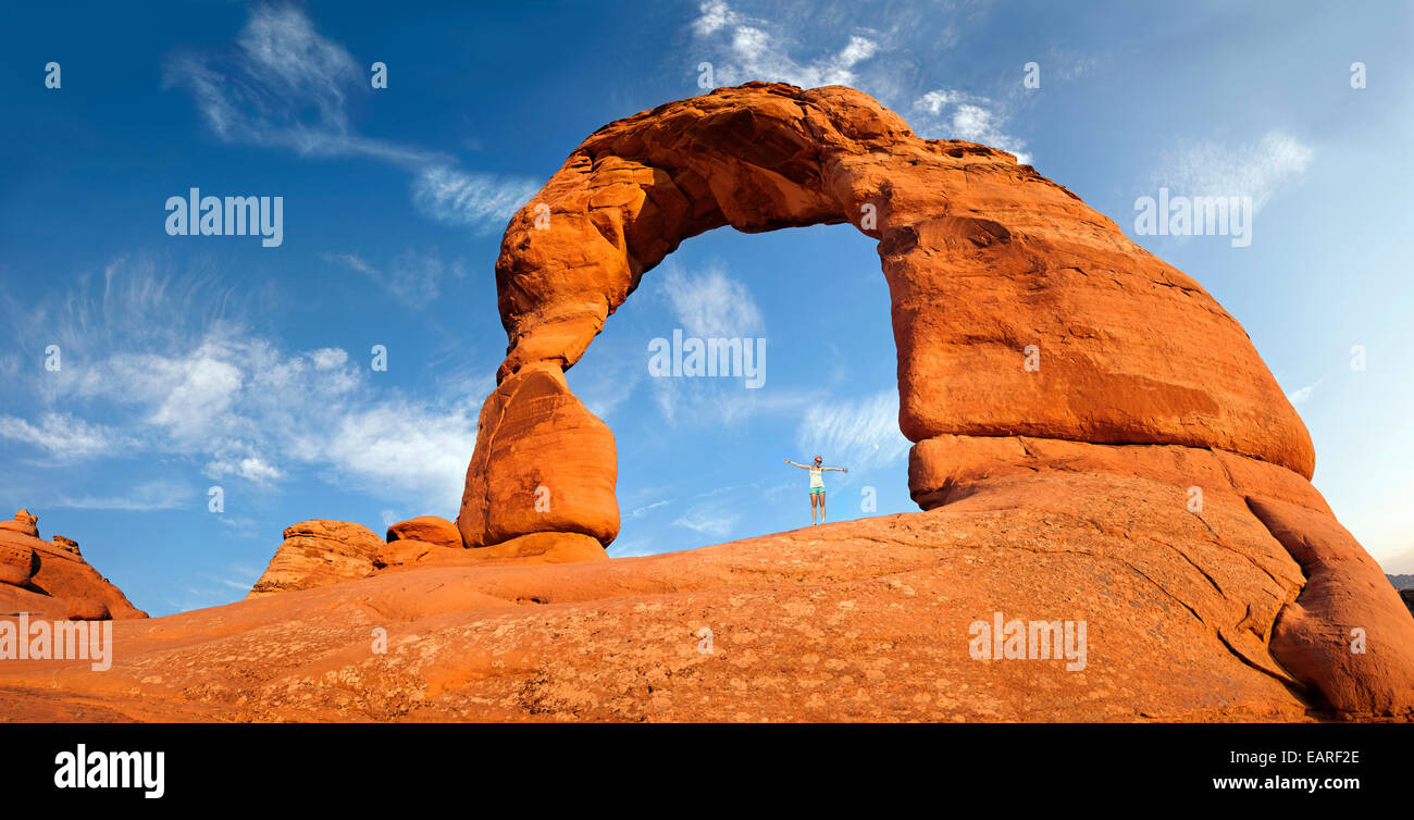 Woman standing under Delicate Arch natural stone arch, Arches-Nationalpark, près de Moab, Utah, United States Banque D'Images