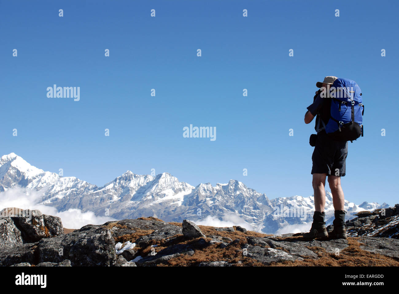 Un trekker sur un chemin dans l'Himalaya indien avec la montagne enneigée du kangchenjunga en arrière-plan Banque D'Images
