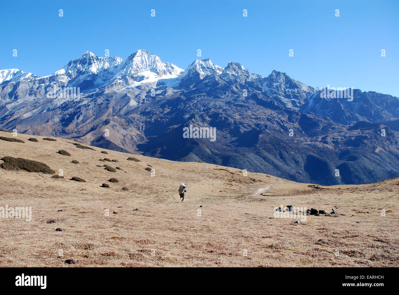 Un porteur se dirige vers les sommets du haut Himalaya Kangchenjunga à proximité dans l'état indien du Sikkim Banque D'Images