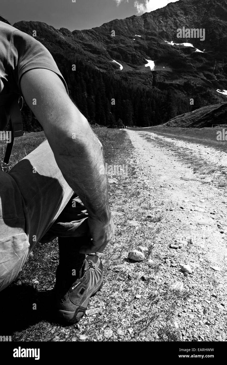 Trekker s'agenouiller pour faire ses lacets, en Suisse. Banque D'Images