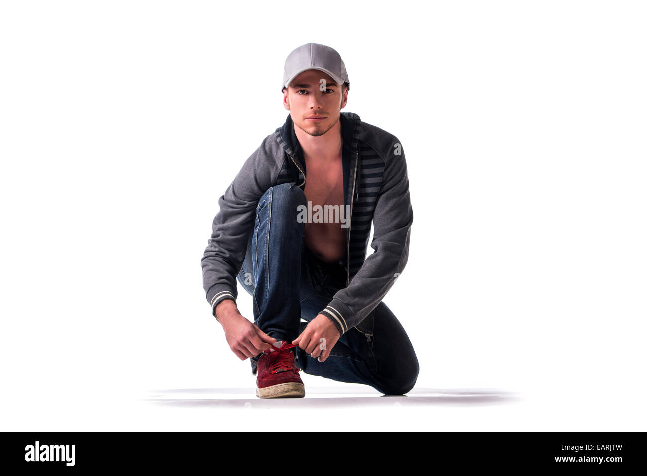 Beau jeune homme à genoux et nouage montrent l'espadrille, prêt à être exécuté. Isolated on white Banque D'Images