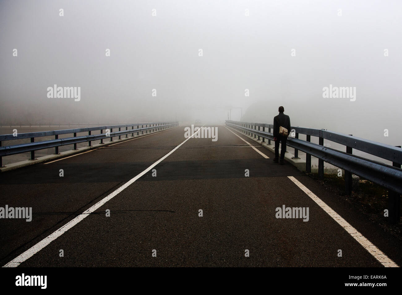 Lone man walking down road avec un épais brouillard. Banque D'Images