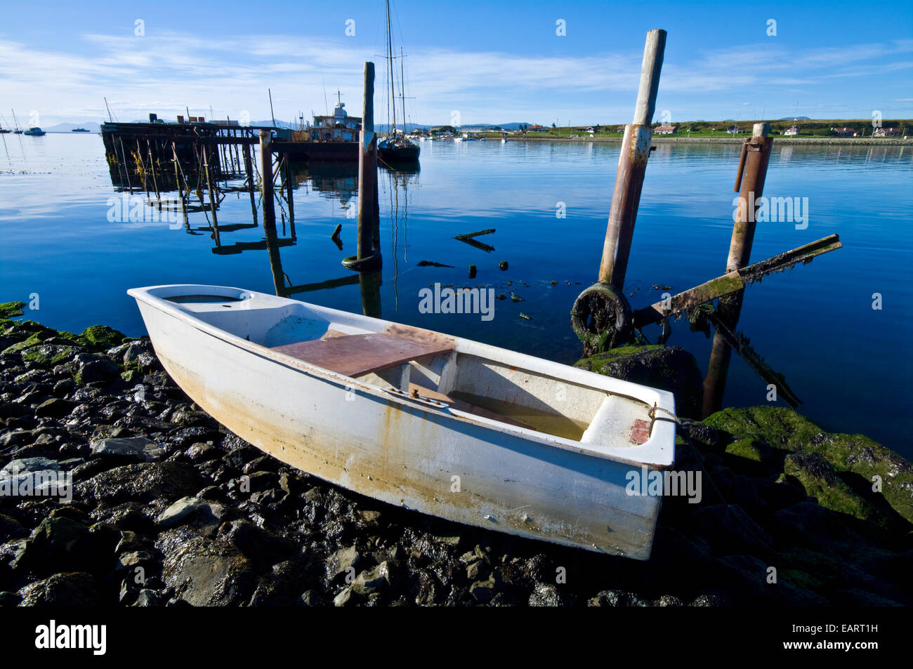 Un petit bateau à aubes échoué sur la côte rocheuse d'un village de pêcheurs. Banque D'Images